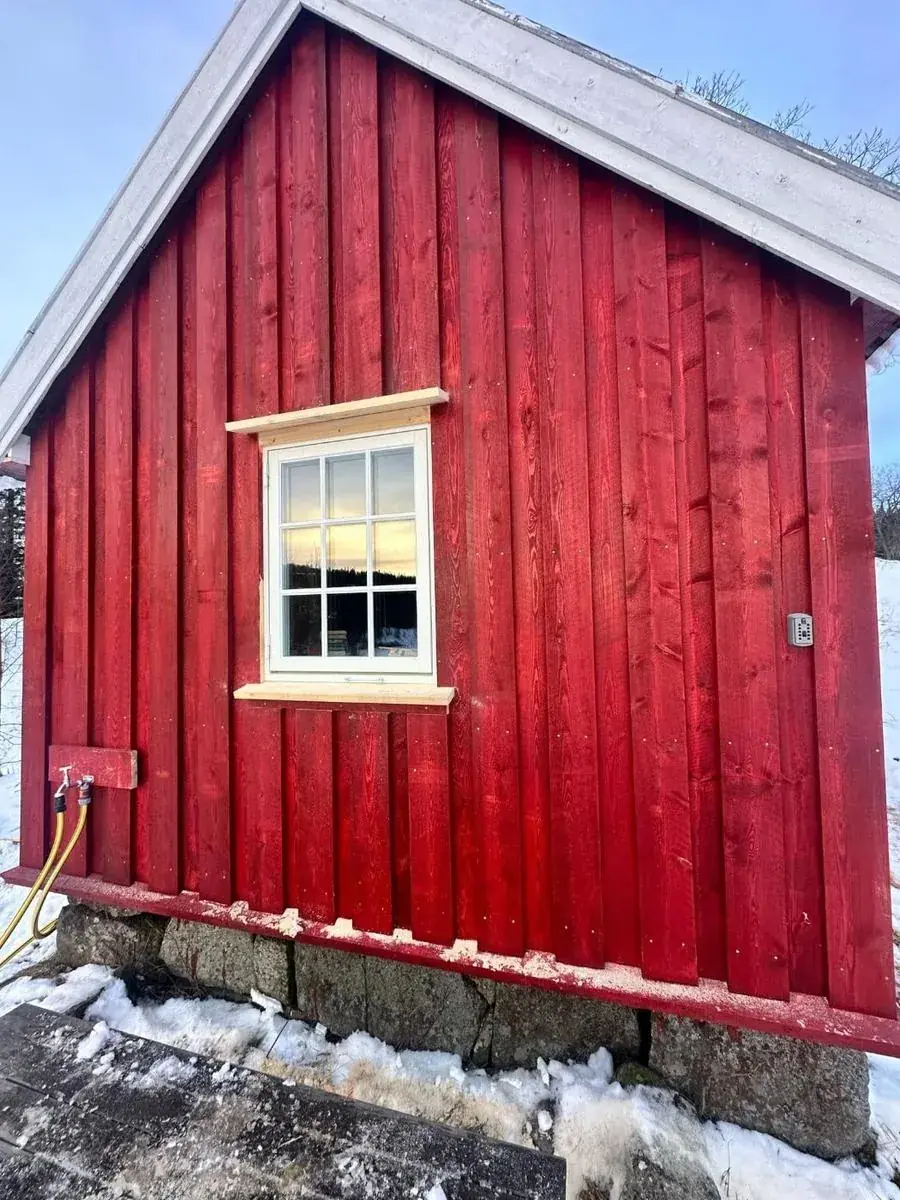 Ny rød kledning og vindu på rehabilitert hus